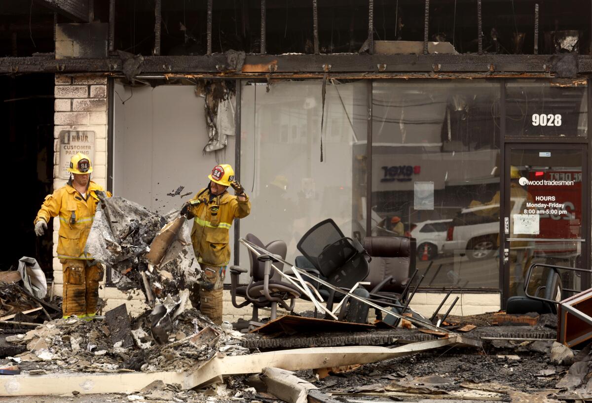 Firefighters clean up after a fire broke in strip mall.