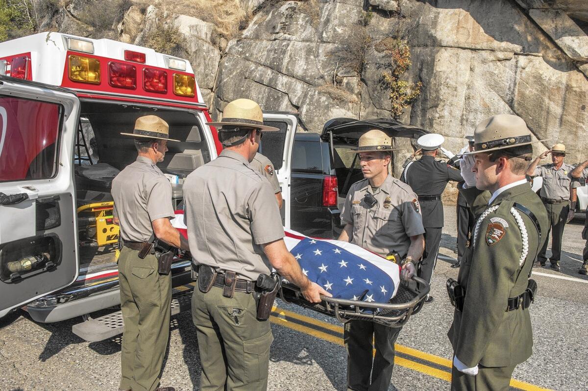 Yosemite National Park rangers transfer to a waiting ambulance the body of a Cal Fire pilot killed in a crash the day before.