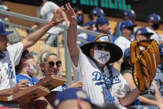 Los Angeles, CA, Friday, April 9, 2021 - A fan with an extra large glove is congratulated after catching a ball in the left field pavilion at Dodger Stadium. (Robert Gauthier/Los Angeles Times)