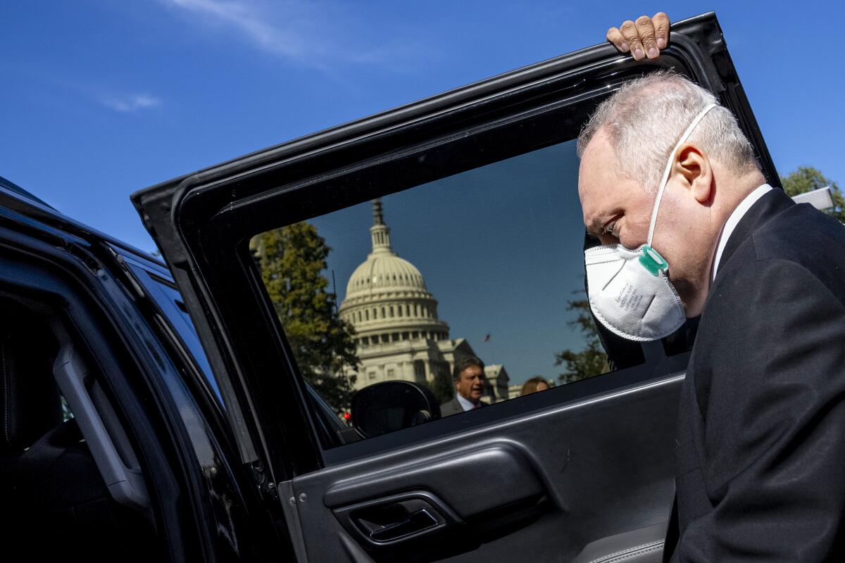 A hand holds a door of a black vehicle open for Steve Scalise near the U.S. Capitol, visible through the door's tinted window