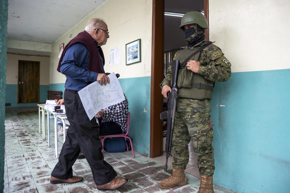 A voter carries a ballot past an armed, masked guard during an election in Quito, Ecuador.