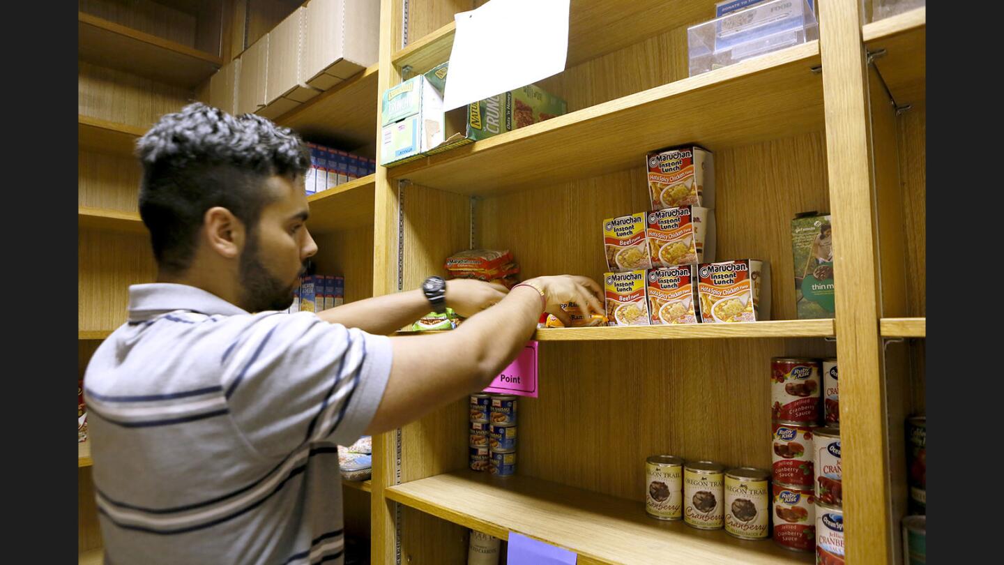 Student volunteer Jose Aquila arranges food donated to the Glendale College food pantry on the Glendale campus on Tuesday, July 11, 2017. Registered students can have 15 points of food items free per week just for signing up.