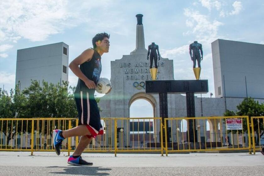 A runner jogs past the entrance to the L.A. Memorial Coliseum.
