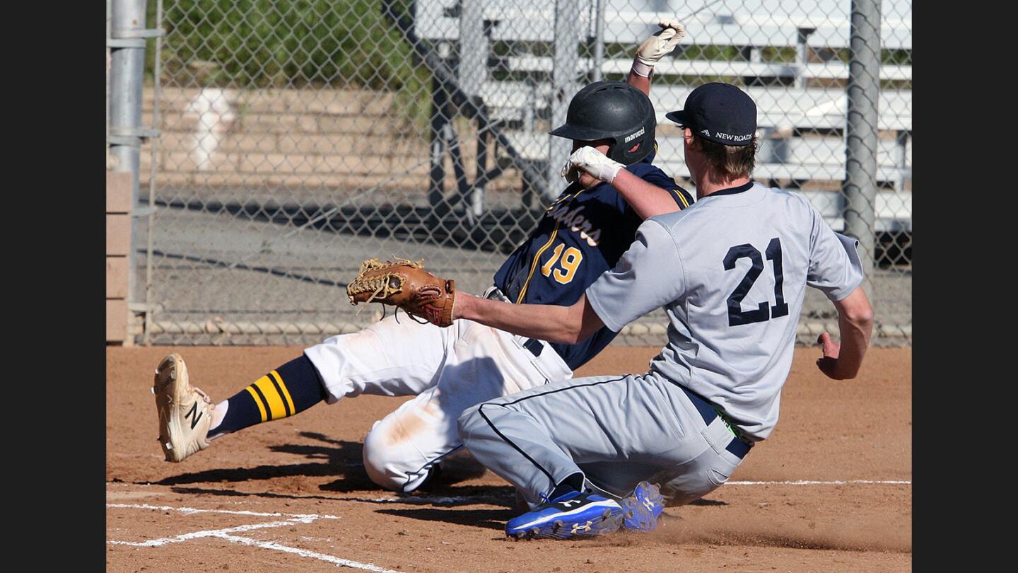 St. Monica Academy's Beau Barry slides home to score, beating the tag by New Roads pitcher Brandon Deutsch who had to run home to try and make a play after a pitch got by the catcher at Scholl Canyon ballfields in Glendale on Thursday, March 23, 2017.