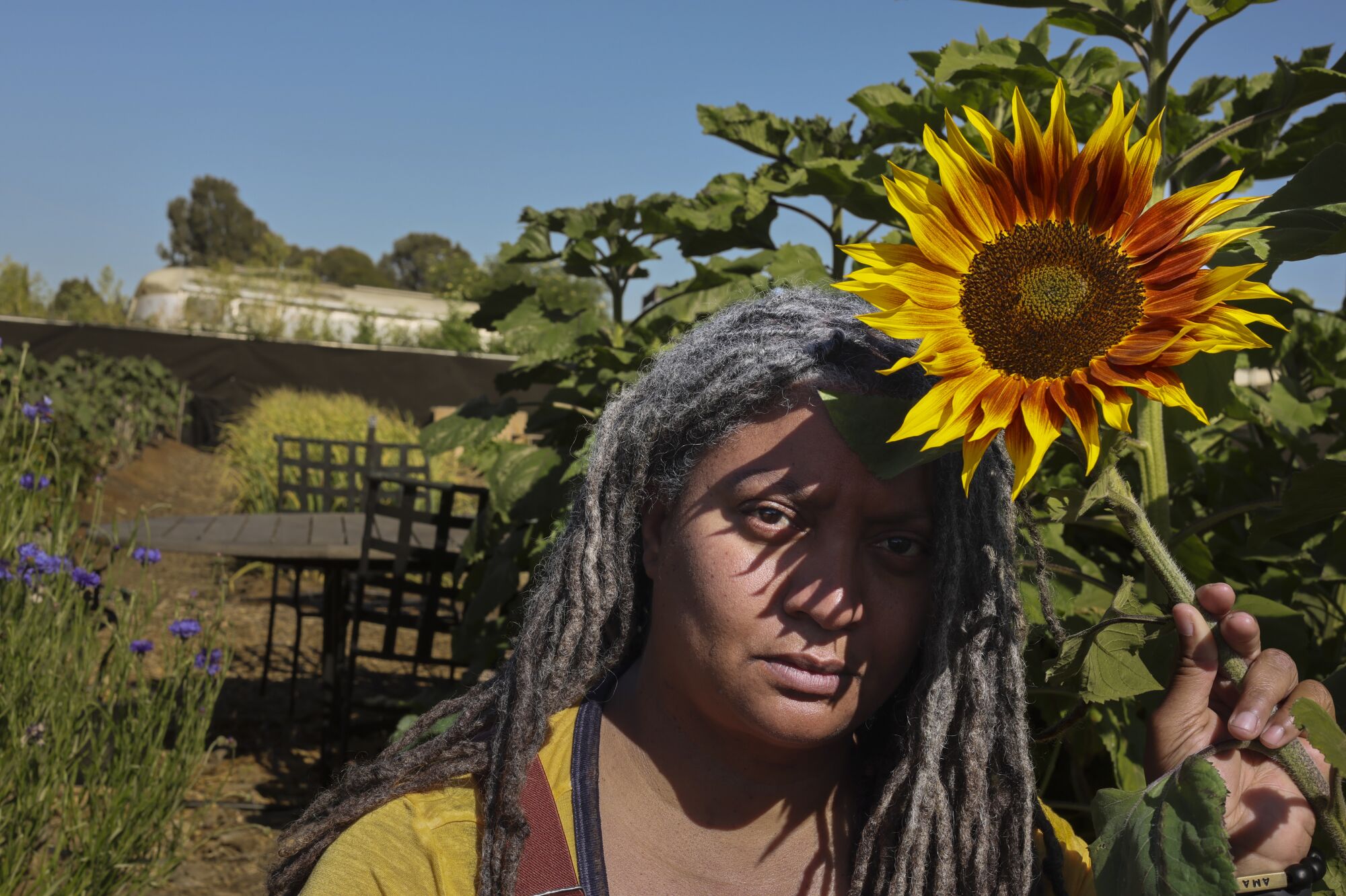 Doria Robinson holding a sunflower in bloom.
