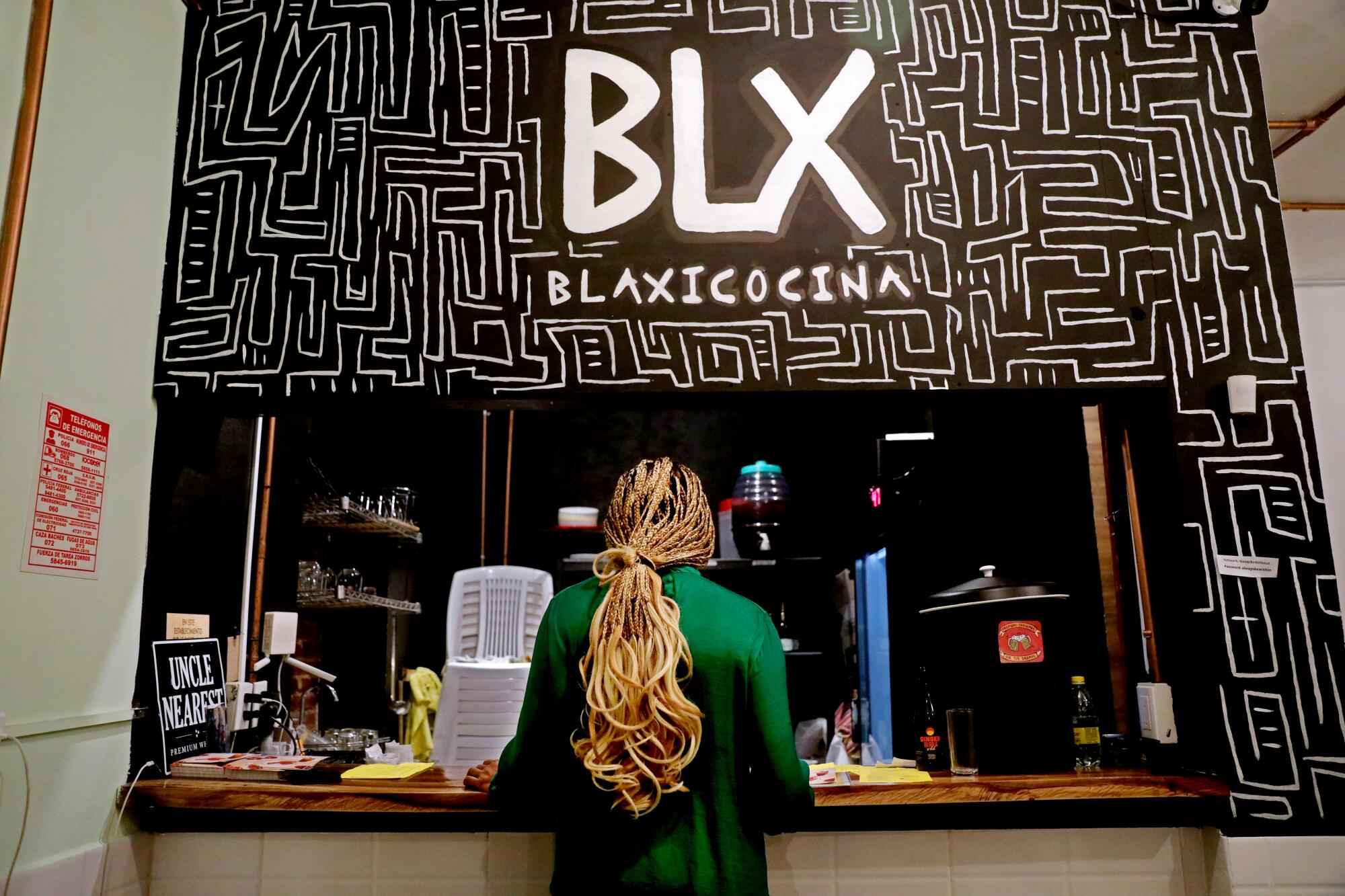 A woman at a restaurant counter under a sign that says "Blaxicocina."