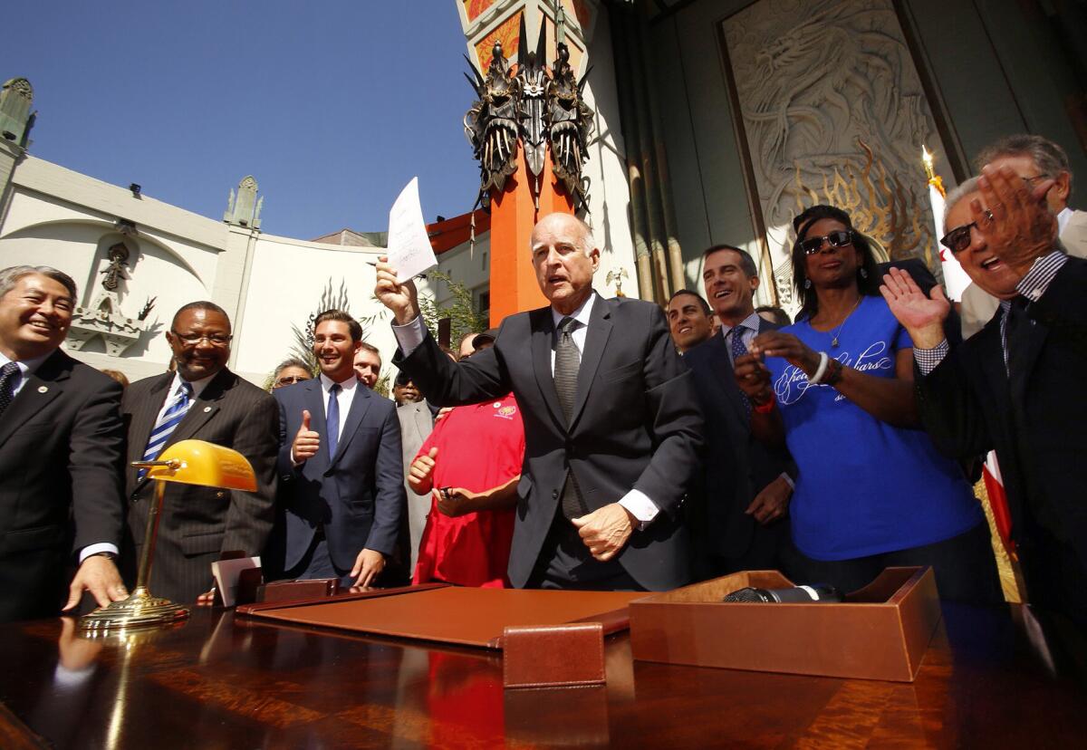 Gov. Jerry Brown holds the new film tax credit bill he signed in front of TLC Chinese IMAX Theatre in Hollywood last year.