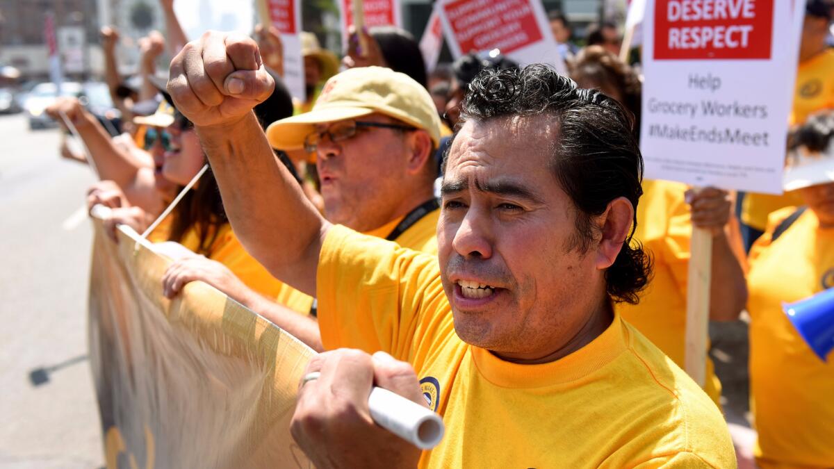 Oscar Gonzalez, a Ralphs produce worker in Hollywood, marches with grocery workers and supporters Tuesday to demand a new contract.