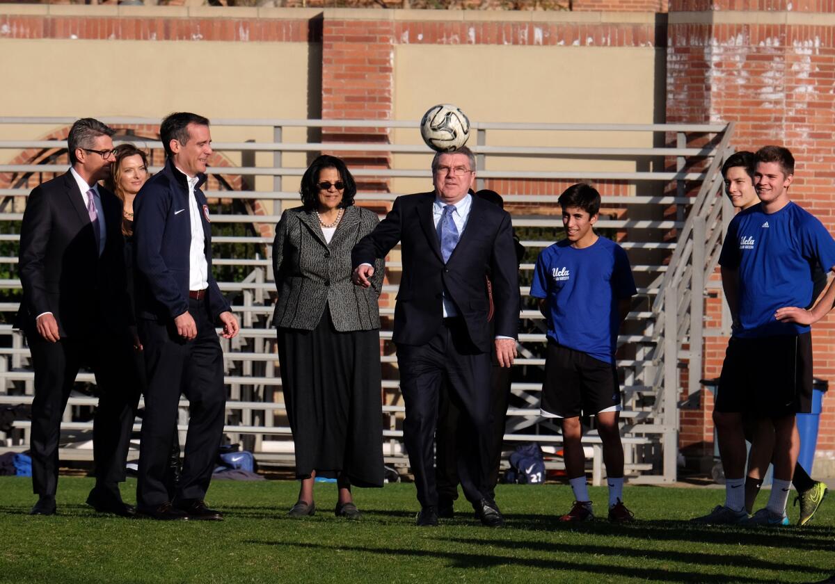 International Olympic Committee President Thomas Bach, center, plays with a soccer ball while watched by Los Angeles Mayor Eric Garcetti, third from left, and UCLA students during a visit to the university.