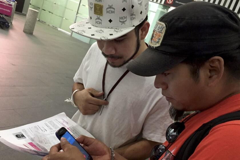 Roger Perez, 21, left, receives help from Diego Maria, 41, who is a part of a group called Deportees United in the Struggle. The group, made up of former deportees, goes to the airport each week to greet those who, like them, have been forced to return.