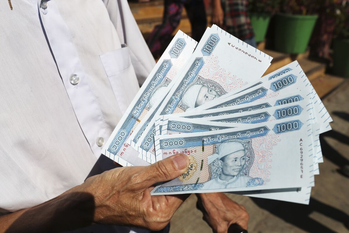 FILE - A man shows new currency notes outside Myanmar Economic Bank Tuesday, Jan. 7, 2020, in Yangon, Myanmar. Than Than Swe, a deputy governor of Myanmar’s Central Bank, was shot at her home Thursday, April 7, 2022, days after the bank ordered that foreign money in bank accounts in Myanmar be exchanged for the local currency. There were conflicting accounts of whether Than Than Swe survived. She appeared to be the most senior official attacked in the violence that has wracked Myanmar since the military seized power in February 2021.(AP Photo/File)