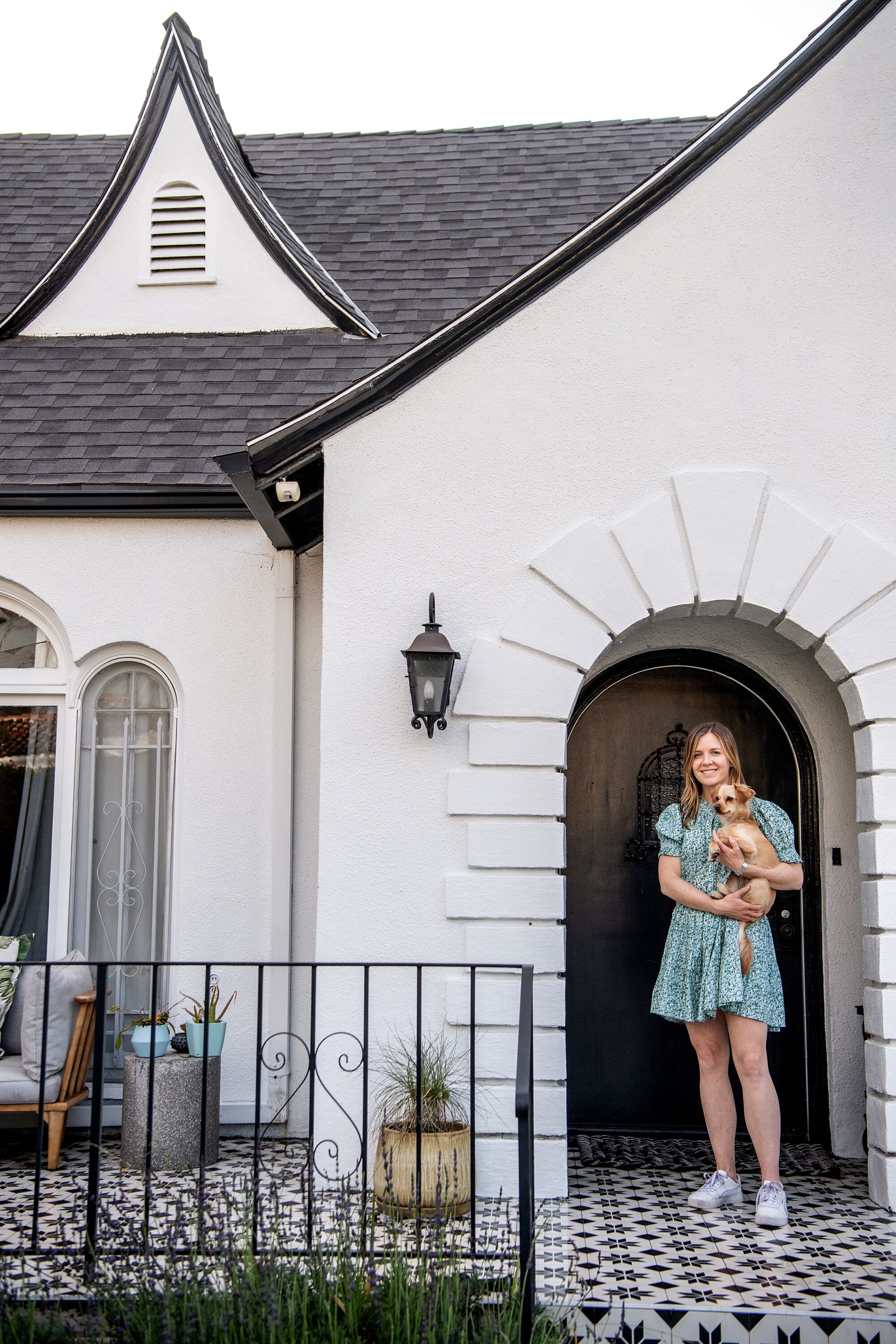 Bridget Bousa stands in front of her house holding a dog.