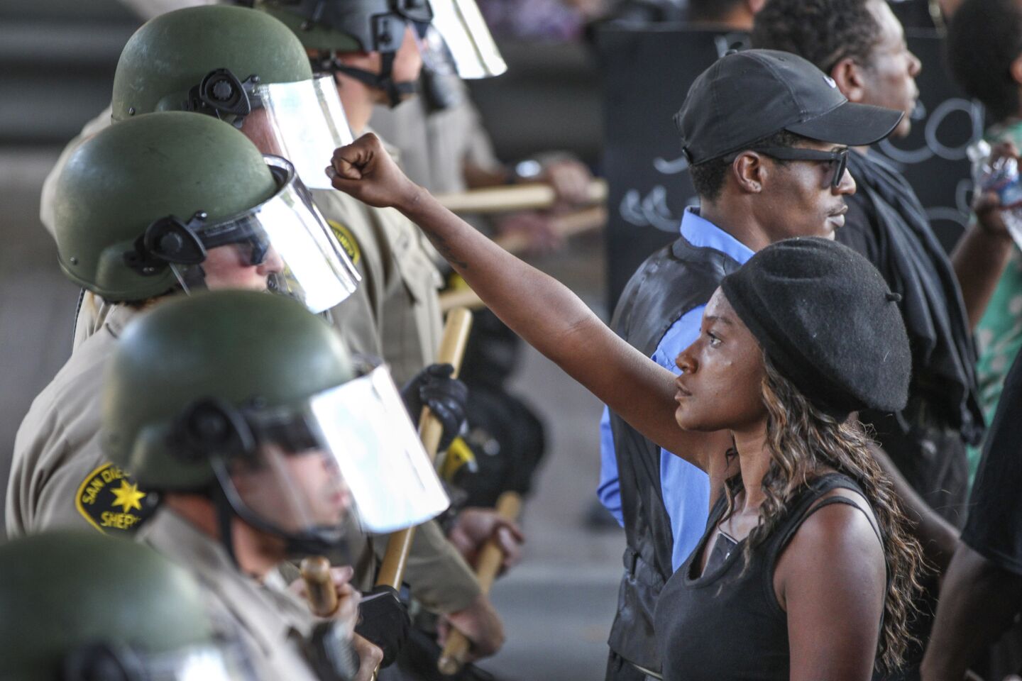 Ebonay Lee holds up her fist toward a line of Sheriff's deputies