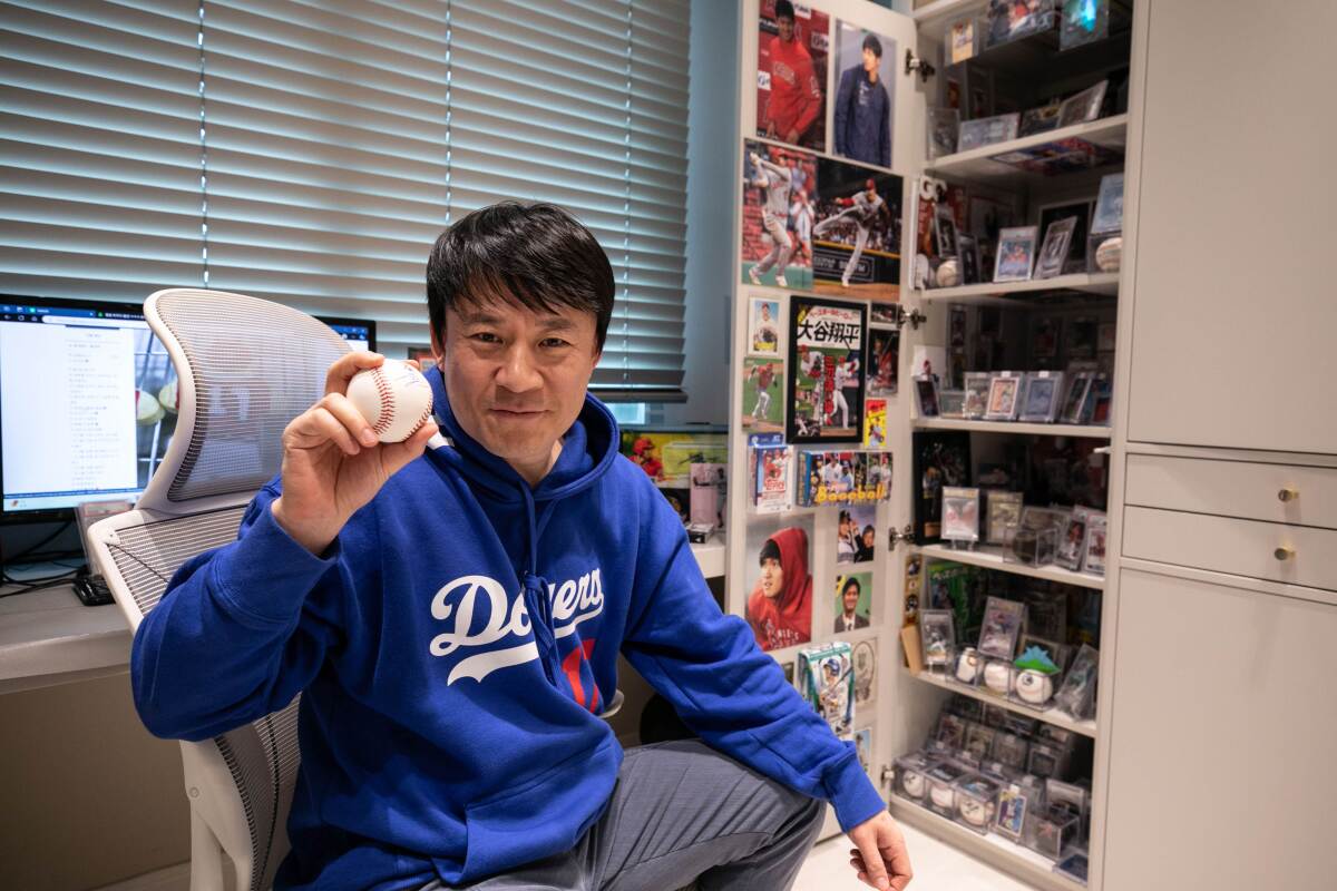 A man holds a signed ball inside a room