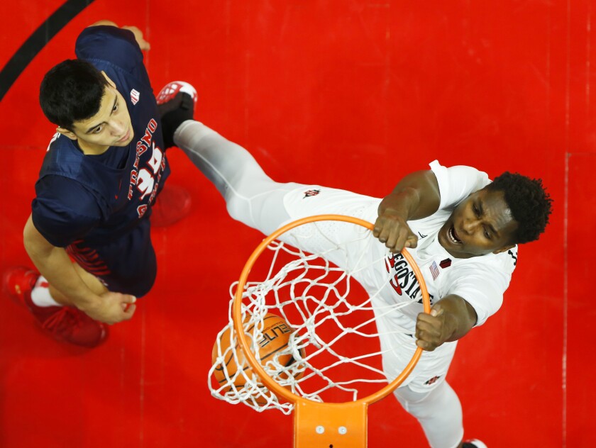 San Diego State's Joel Mensah (right) slam dunks in front of Fresno State's Lazaro Rojas in Saturday's 61-52 win.