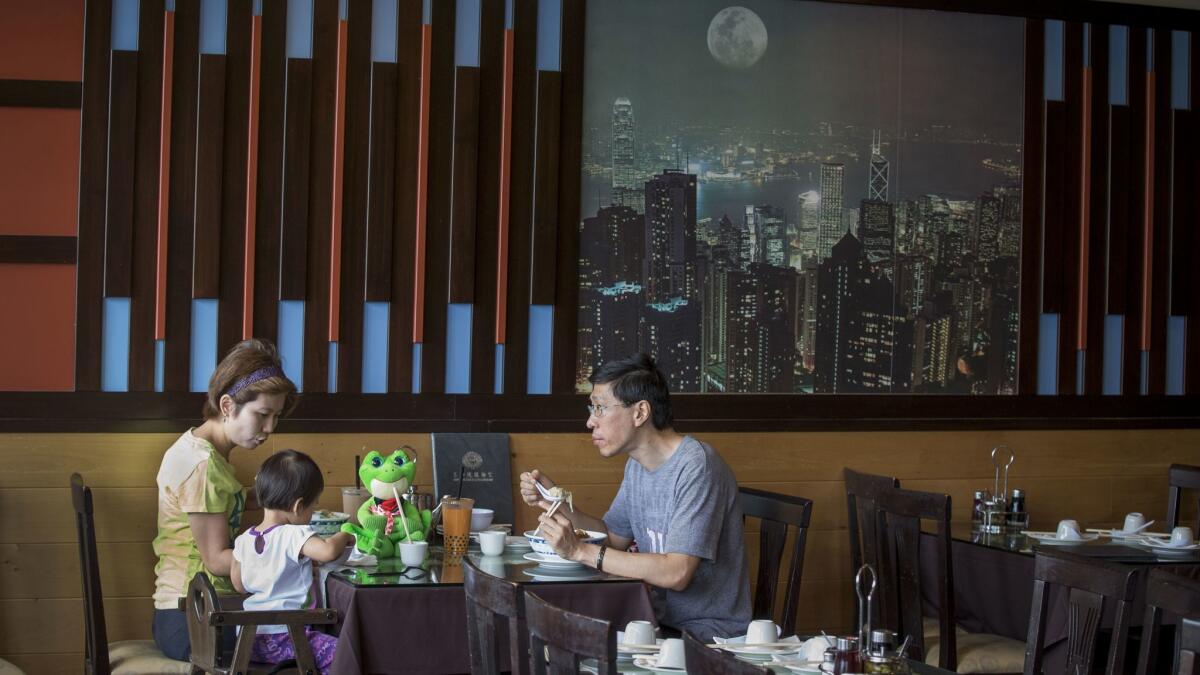 For tasty Cantonese meals, families flock to one of the city's most popular eateries, Sam Woo. In the background, a picture of Hong Kong. (Allen J. Schaben / Los Angeles Times)