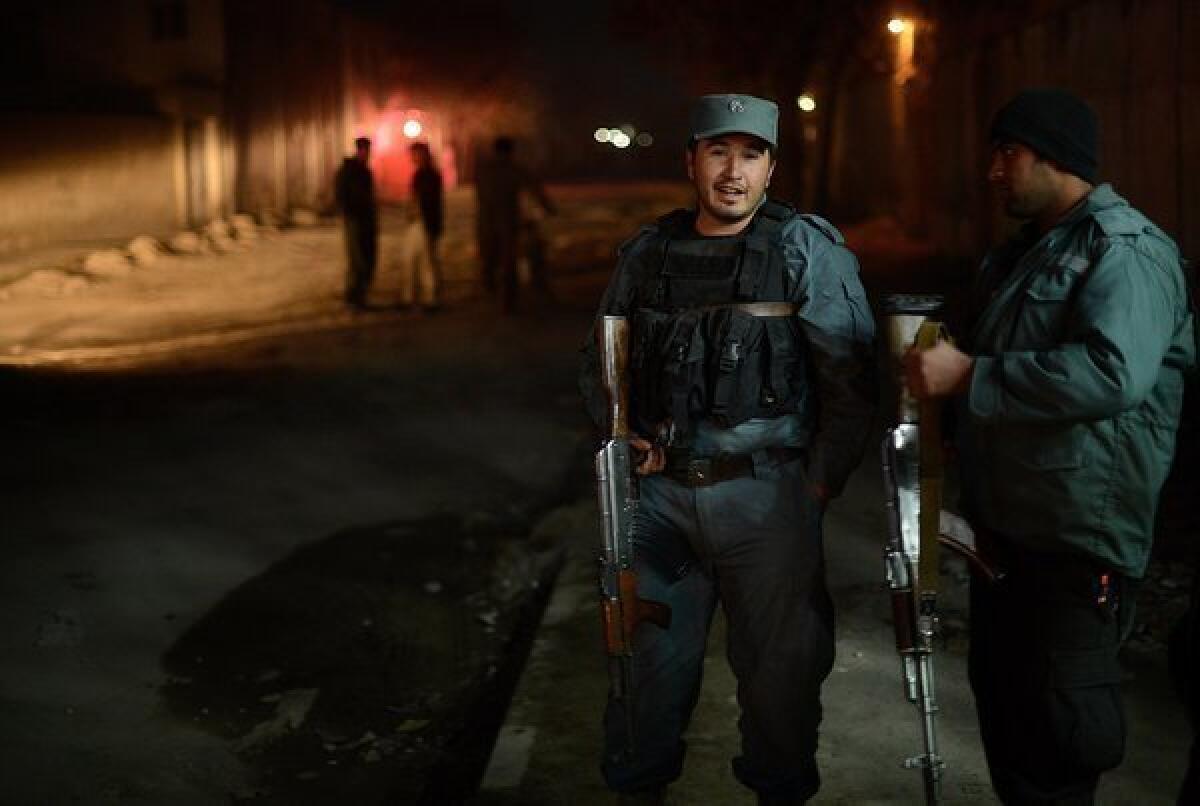 Afghan policemen block a road near the site of an attack at a spy agency guest house in Kabul, Afghanistan.