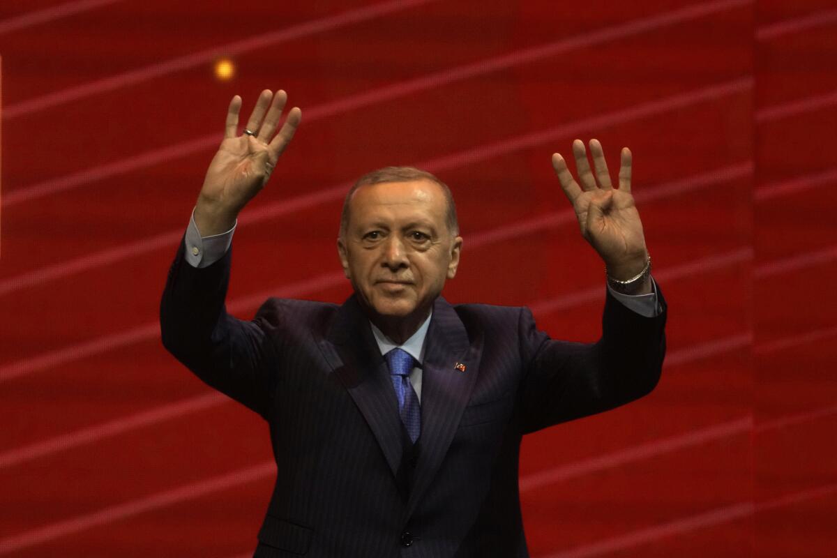 Erdogan waves before a red backdrop 