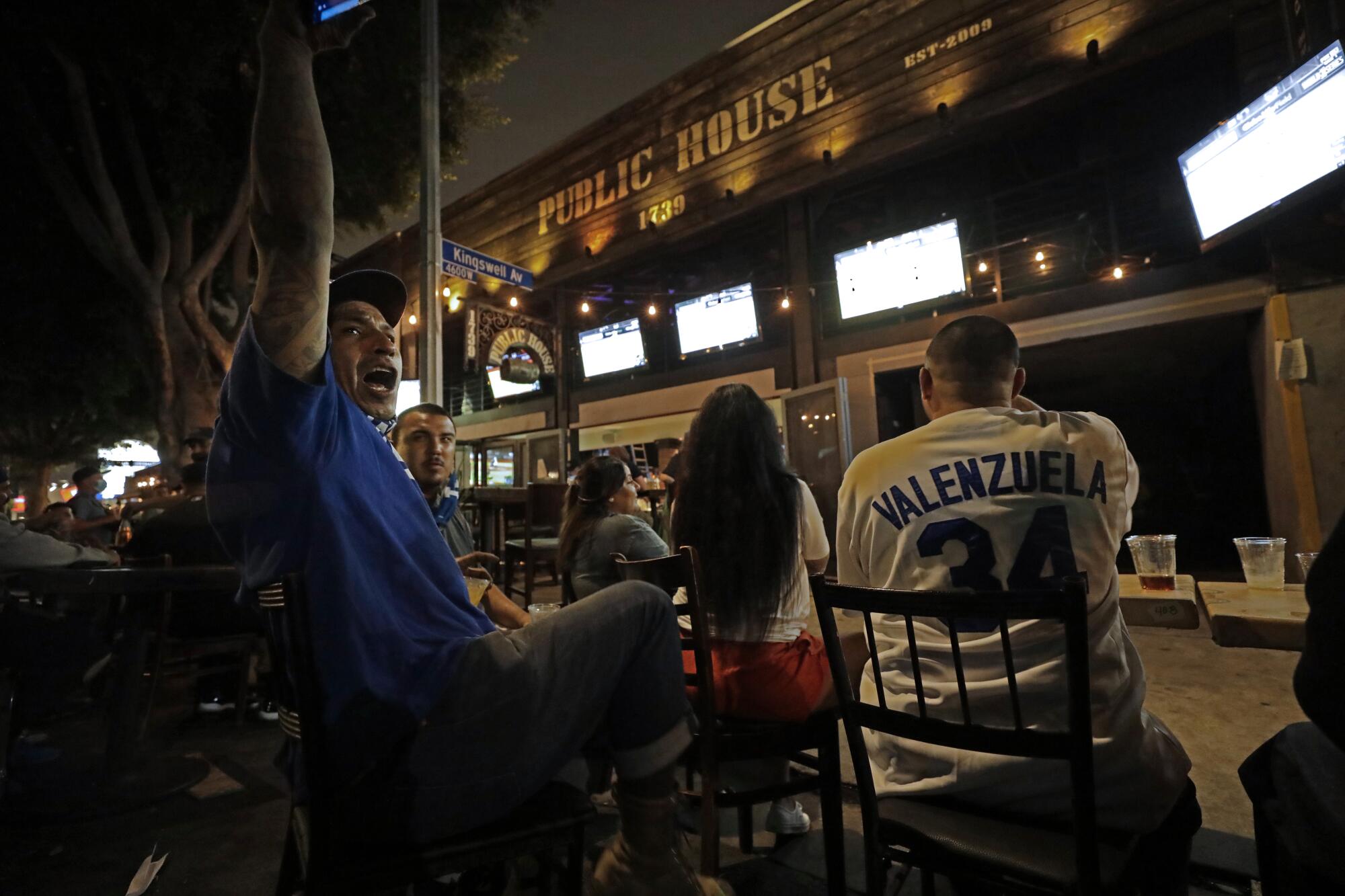 Dodgers fan Jose Manuel Zepeda cheers on a passing car honking in support of the Dodgers while watching the game 