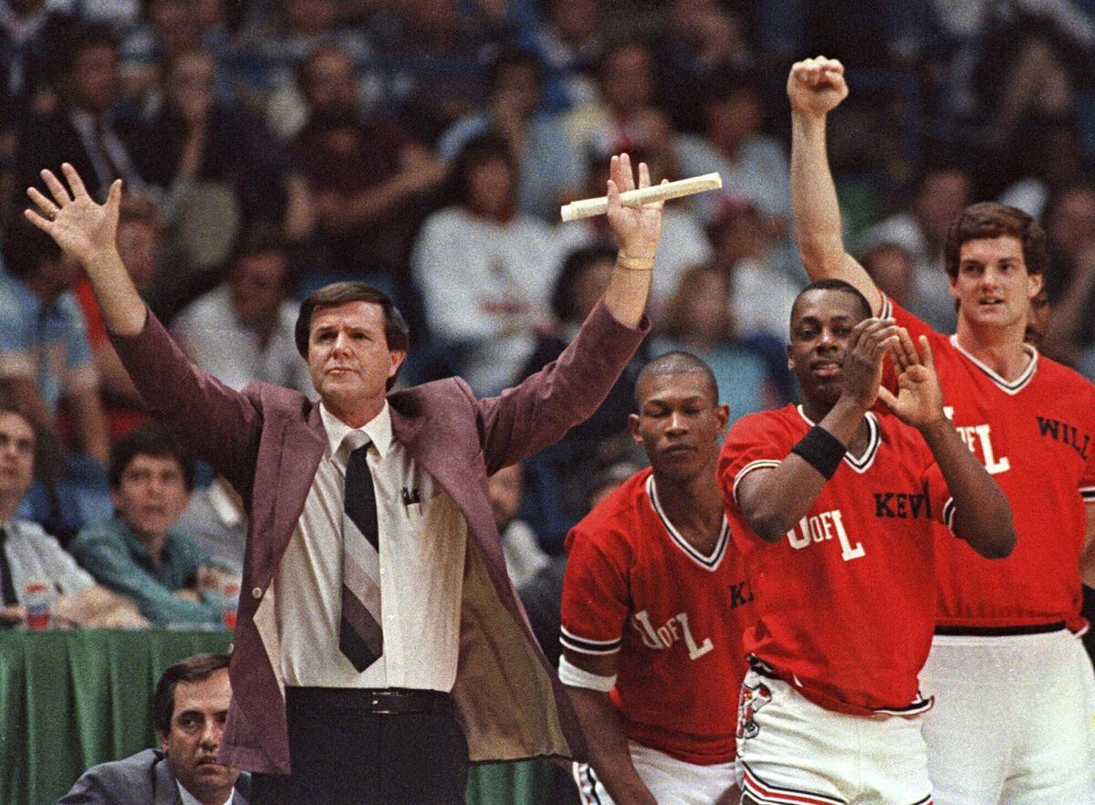 Louisville coach Denny Crum gestures towards his team as players from the bench begin to celebrate.
