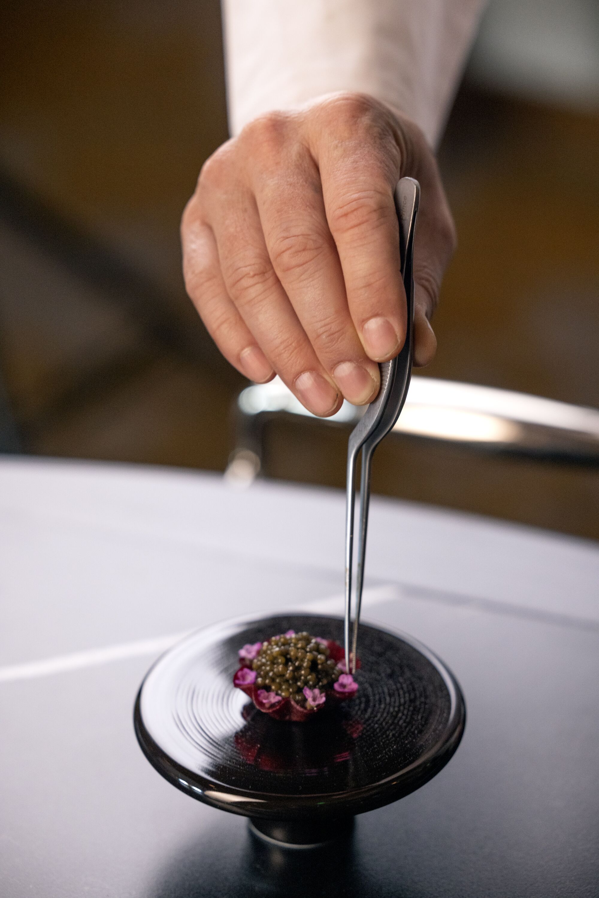 Chef-Director William Bradley uses a tweezers on a tiny caviar and beet tart at Addison restaurant.