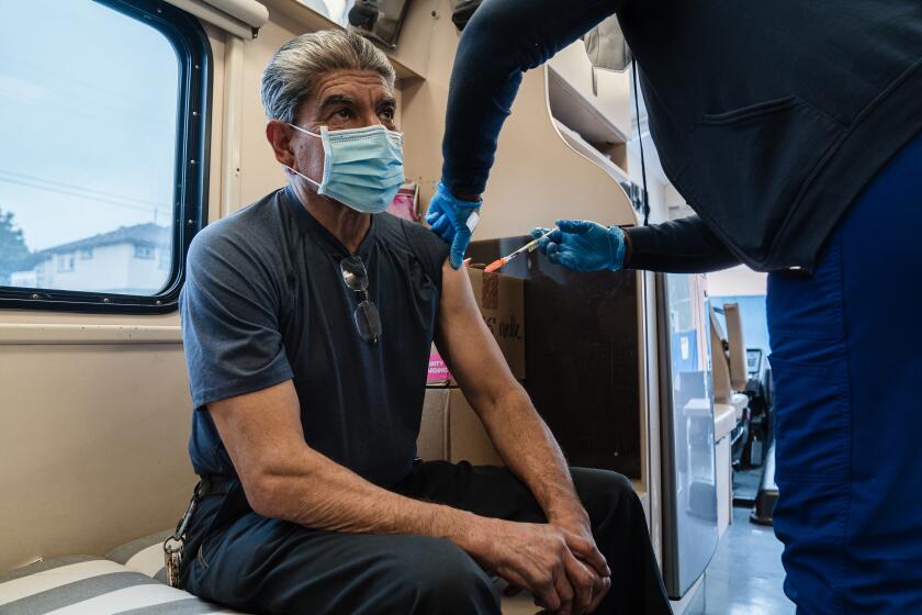 Hector Sanchez, an auto mechanic for Fleet Services for San Diego Unified receives the Moderna booster shot for COVID-19 at the UC San Diego Health Mobile Vaccine Clinic at Crawford High School in El Cerrito on January 12, 2022.