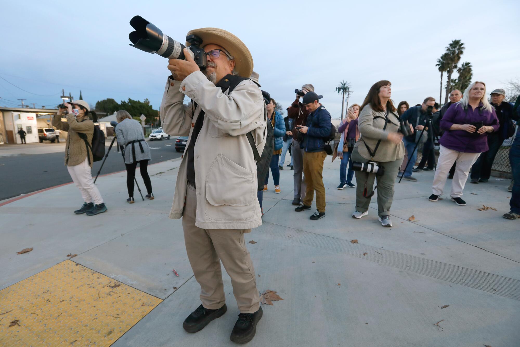 A photographer lifts his lens to the sky.