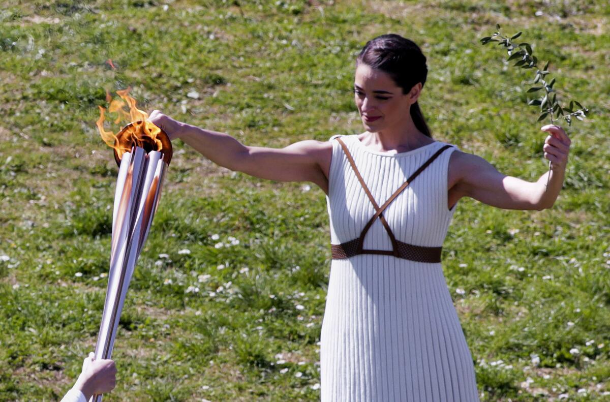 Greek actress Xanthi Georgiou, playing the role of High Priestess, passes the flame to the first torchbearer.