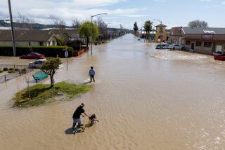 An aerial view shows people making their way around a flooded neighborhood in the unincorporated community of Pajaro in Watsonville, California on March 11, 2023. - Residents were forced to evacuate in the middle of the night after an atmospheric river surge broke the Pajaro Levee and sent flood waters flowing into the community. (Photo by JOSH EDELSON / AFP) (Photo by JOSH EDELSON/AFP via Getty Images)