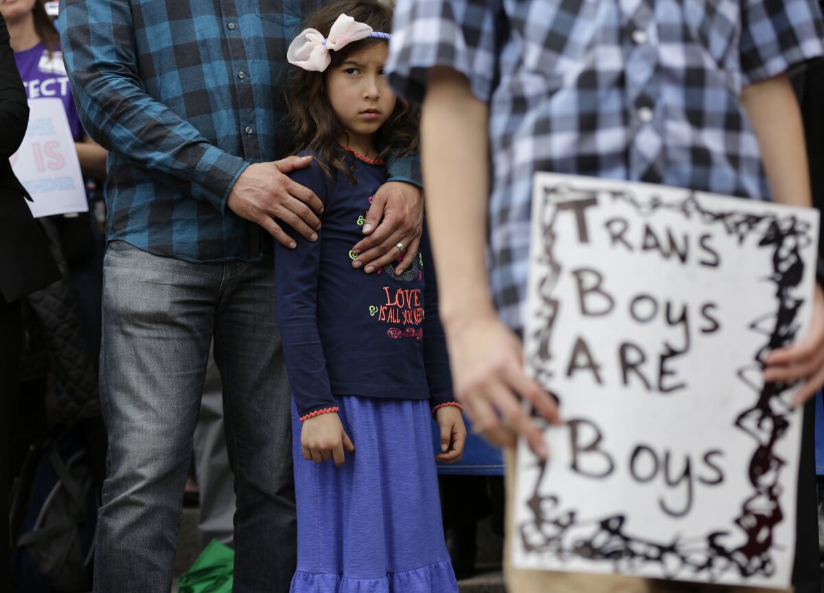 FILE - Libby Gonzales stands with her father, Frank Gonzales, as she joins other members of the transgender community during a rally on the steps of the Texas Capitol, Monday, March 6, 2017, in Austin, Texas. The group is opposing a "bathroom bill" that would require people to use public bathrooms and restrooms that correspond with the sex on their birth certificate. (AP Photo/Eric Gay, File)