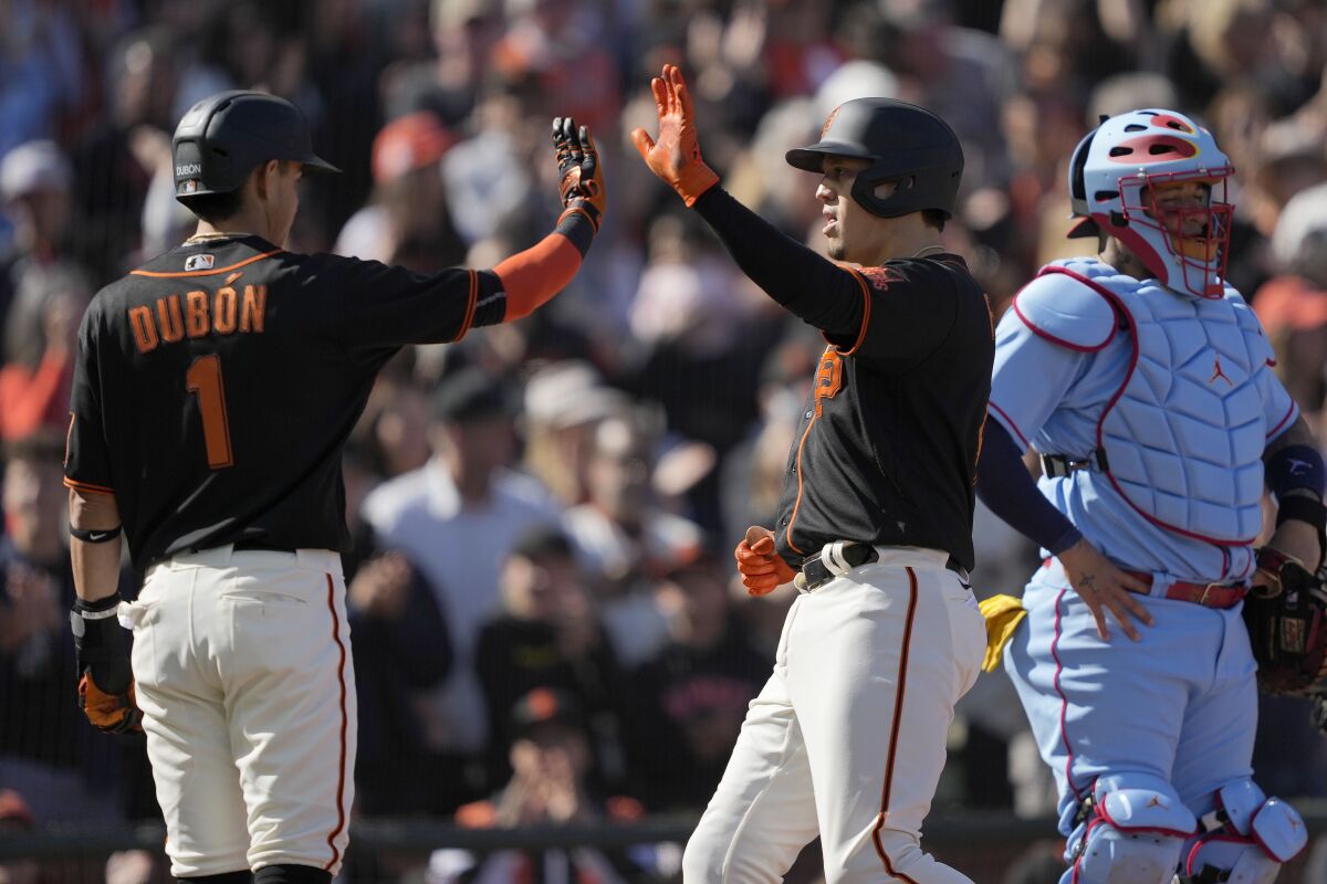 San Francisco Giants' Wilmer Flores, right, is congratulated by Mauricio Dubon (1) as he crosses home plate after hitting a grand slam against the St. Louis Cardinals during the first inning of a baseball game Saturday, May 7, 2022, in San Francisco. (AP Photo/Tony Avelar)