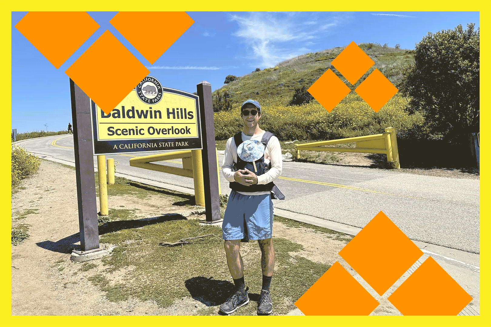 A man holding a newborn at the trailhead for a hike.
