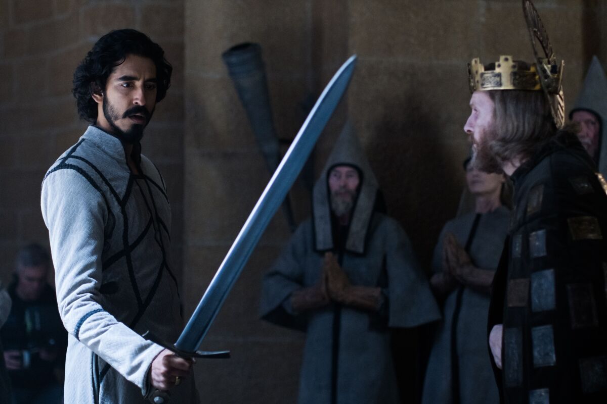 Sean Harris as King Arthur and Dev Patel as Gawain holding a sword in "The Green Knight"
