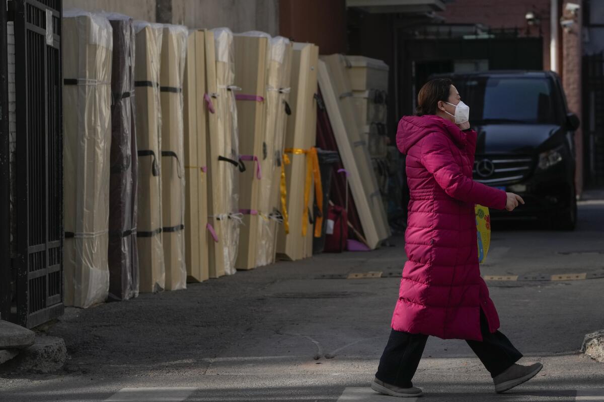 Woman walking by wrapped, upright empty coffins