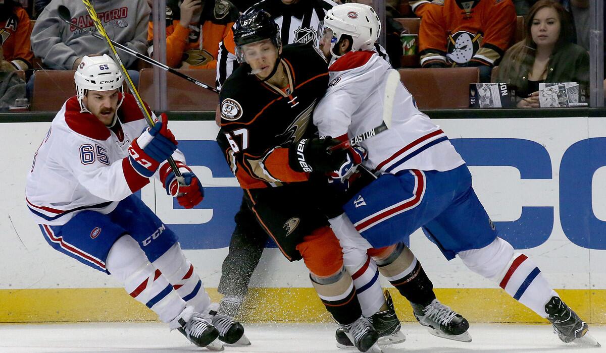 Ducks center Rickard Rakell, center, battles for control of the puck against Canadiens defensemen Mikhail Sergachev, left, and Greg Pateryn in the first period Tuesday.