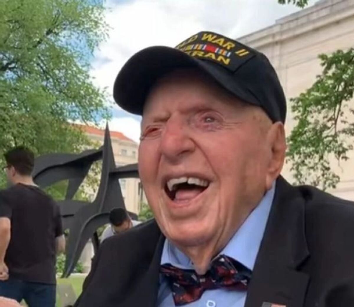 A closeup of Sidney Walton, who smiles and wears a baseball cap identifying him as a U.S. Army veteran of World War II.