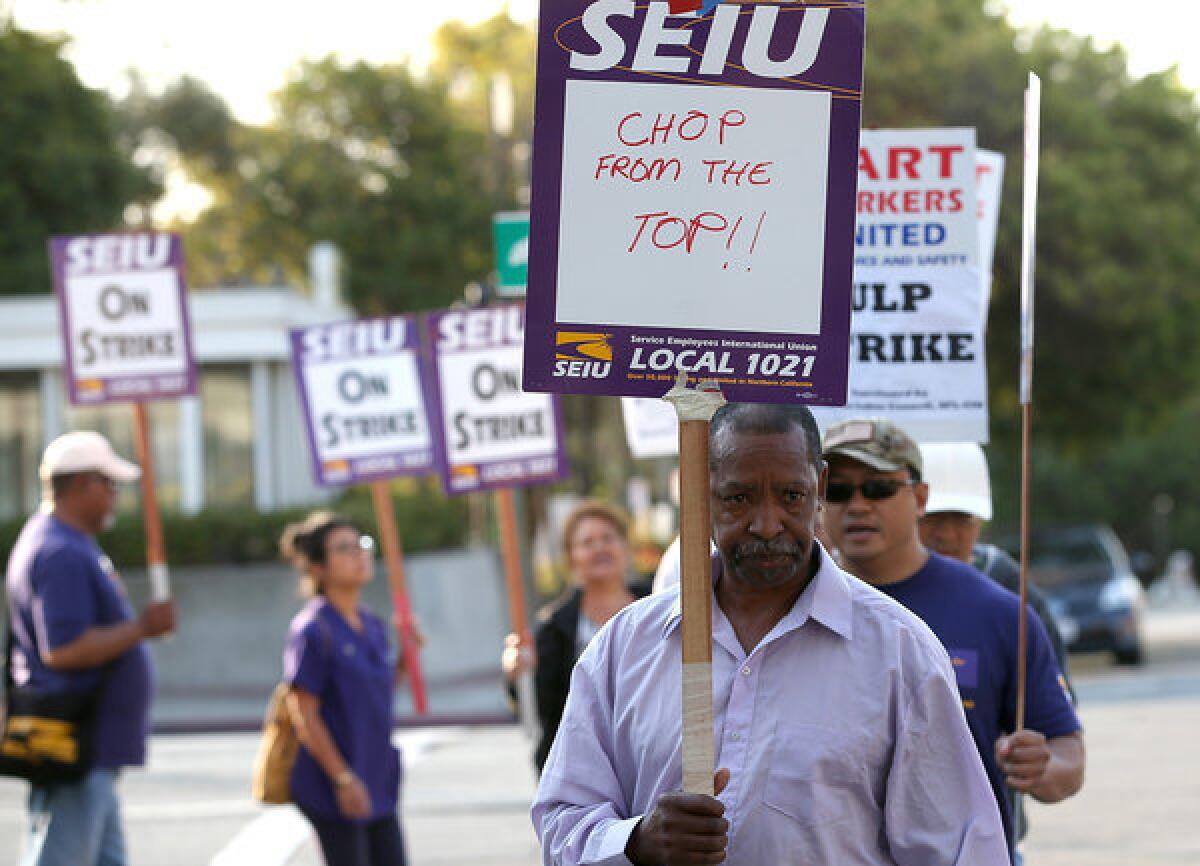 Bay Area Rapid Transit workers with SEIU Local 1021 carry signs in front of the Lake Merritt station in Oakland on Tuesday.