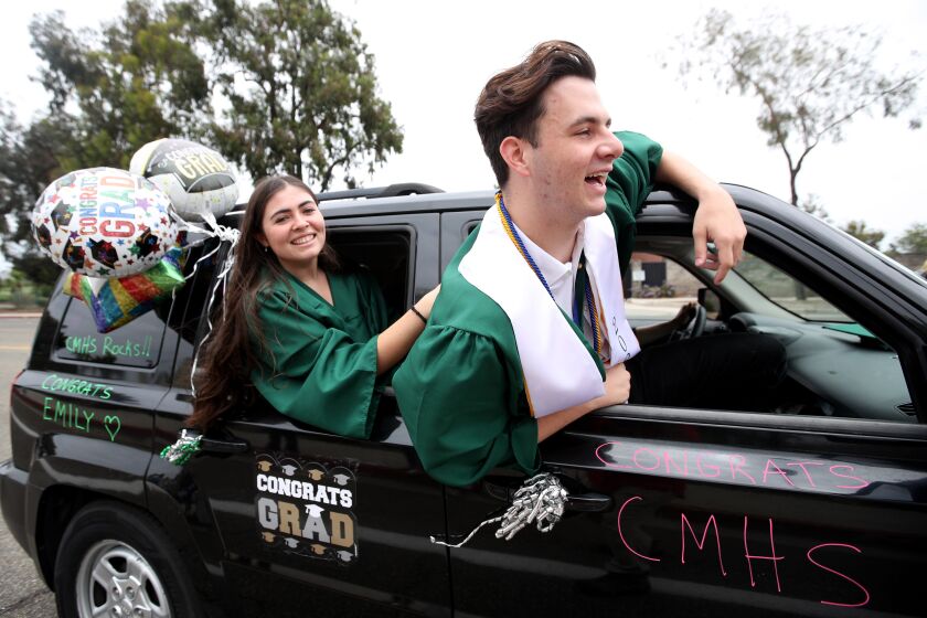Costa Mesa High School graduates stick out car windows as they pass Estancia High School at the end of the Community of Newport Mesa Unified School District Senior Parade Class of 2020, in Costa Mesa on Wednesday, June 17, 2020. The car parade began at Newport Harbor High and wound its way past local high schools before ending at Estancia High.