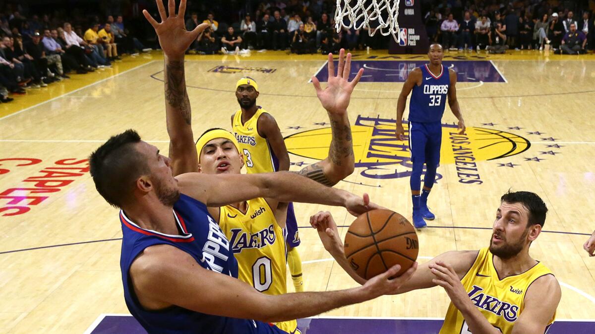 Clippers forward Danilo Gallinari is fouled by Lakers forward Kyle Kuzma as he drives to the basket during first half of their season opener.