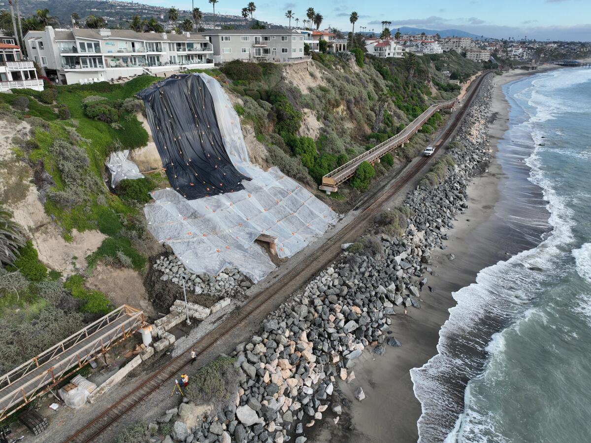 Workers shore up a landslide with plastic tarps after it damaged the Mariposa Bridge and shut down rail service in January