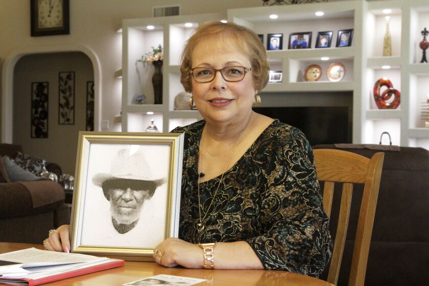 In this April 30, 2019, photo, Arlinda Valencia poses at her home in El Paso, Texas, with a portrait of her great-grandfather Longino Flores, who was murdered at the age of 44 by Texas Rangers and U.S. Army soldiers in the Porvenir Massacre of 1918. As the U.S. prepares to remember the 100th anniversary of "Red Summer," a period in 1919 when white mobs attacked and murdered African Americans in dozens of cities across the country, some historians and Latino activists say now also is the time to acknowledge the terror experienced by Mexican Americans right before that brutal year. (AP Photo/Cedar Attanasio)