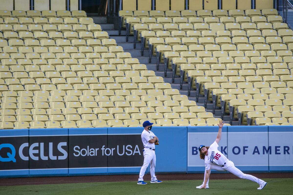 Dodgers starting pitcher Dustin May stretches in front of empty seats before the Dodgers' season opener.