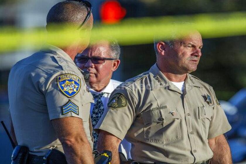 Riverside County Sheriff Chad Bianco, right, with Riverside City Police Chief Sergio G. Diaz, center, and a California Highway Patrol officer gather information after a shootout near a freeway killed a CHP officer and wounded two others before the gunman was fatally shot, Monday, Aug. 12, 2019, in Riverside, Calif. (Terry Pierson/The Orange County Register via AP)