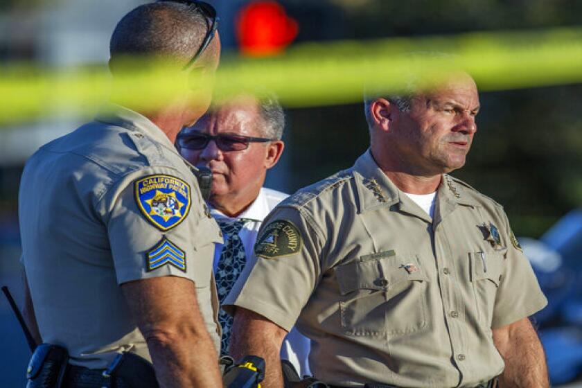 Riverside County Sheriff Chad Bianco, right, with Riverside City Police Chief Sergio G. Diaz, center, and a California Highway Patrol officer gather information after a shootout near a freeway killed a CHP officer and wounded two others before the gunman was fatally shot, Monday, Aug. 12, 2019, in Riverside, Calif. (Terry Pierson/The Orange County Register via AP)