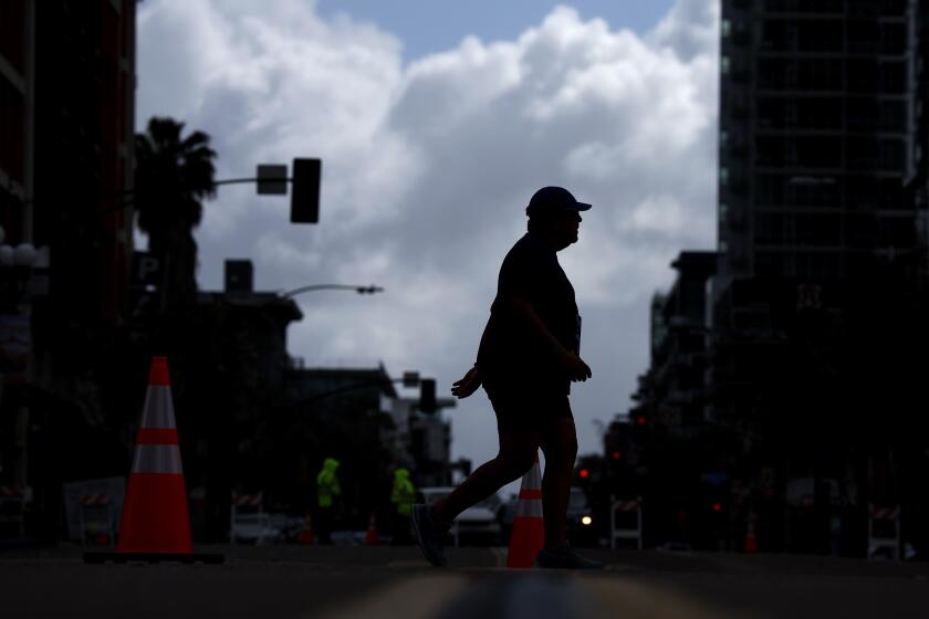 San Diego CA - March 24: A runner heads down 5th Ave. in the Gaslamp Quarter towards the finish of the 13th annual GOVX San Diego Half Marathon on Sunday, March 24, 2024. High winds and light rain took place during the morning race. (K.C. Alfred / The San Diego Union-Tribune)