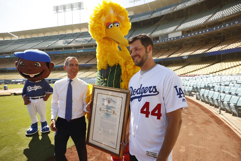 LOS ANGELES, CA - AUGUST 2, 2019 LA Mayor Eric Garcetti, left, with Los Angeles Dodgers pitcher Rich Hill, right, pose with Sesame Street's Big Bird at Dodger Stadium as the Mayor declared Friday August 2, 2019 "Sesame Street Day in LA," bringing the show's 10-city summer road trip to mark the shows 5oth anniversary to an end here. (Al Seib / Los Angeles Times)