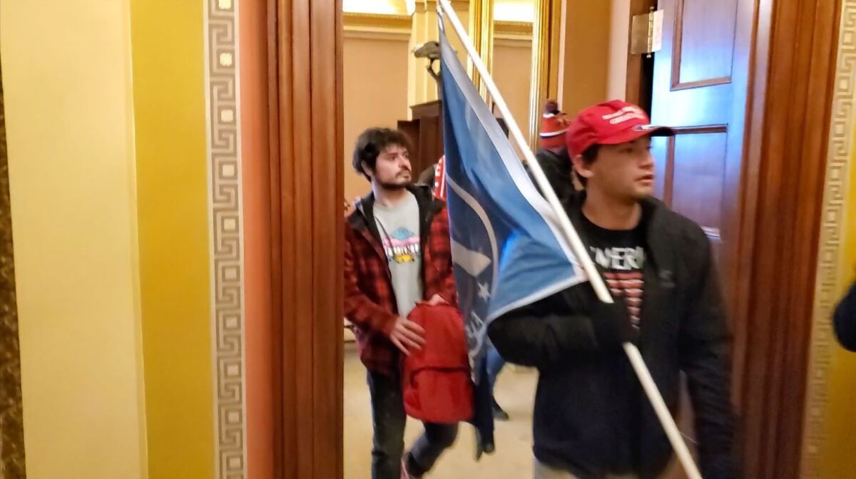 Christian Secor, of Costa Mesa, carries a flag while walking through the Capitol on Jan. 6, 2021. 