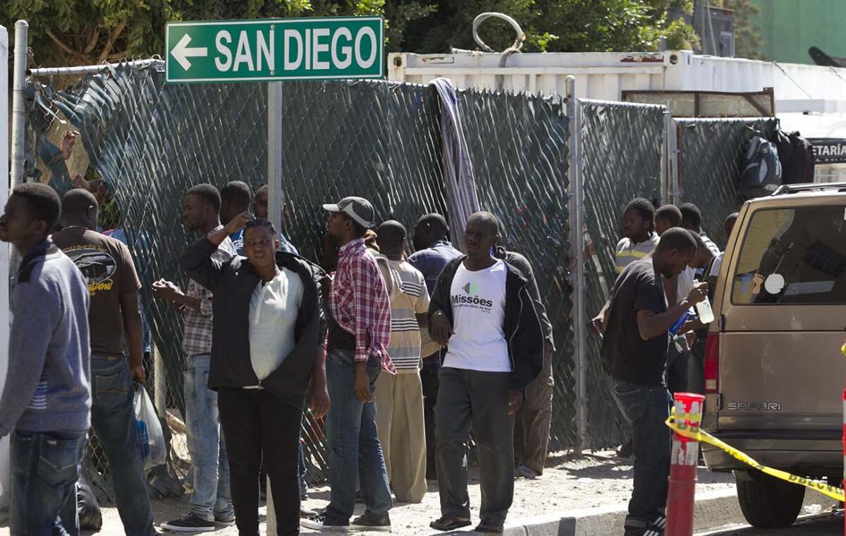 People stand near a sign that says "San Diego" with an arrow pointing left