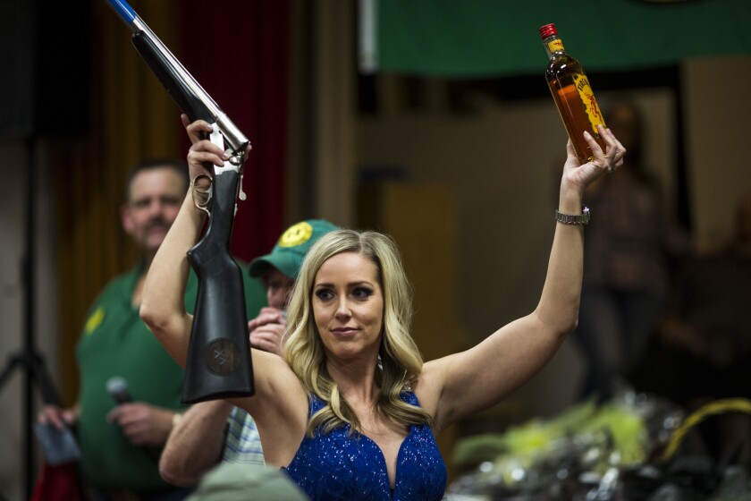Candace Smith holds a shotgun and a bottle of whiskey during a fundraising auction last month in Anderson, Calif.