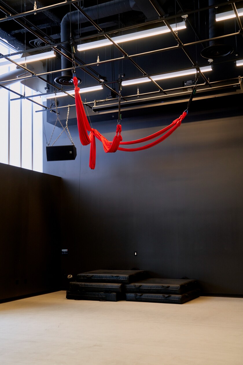 Red aerial silks are seen in an empty aerial studio.